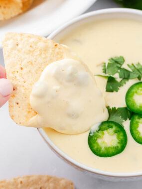 Dipping a tortilla chip in a bowl of queso blanco.