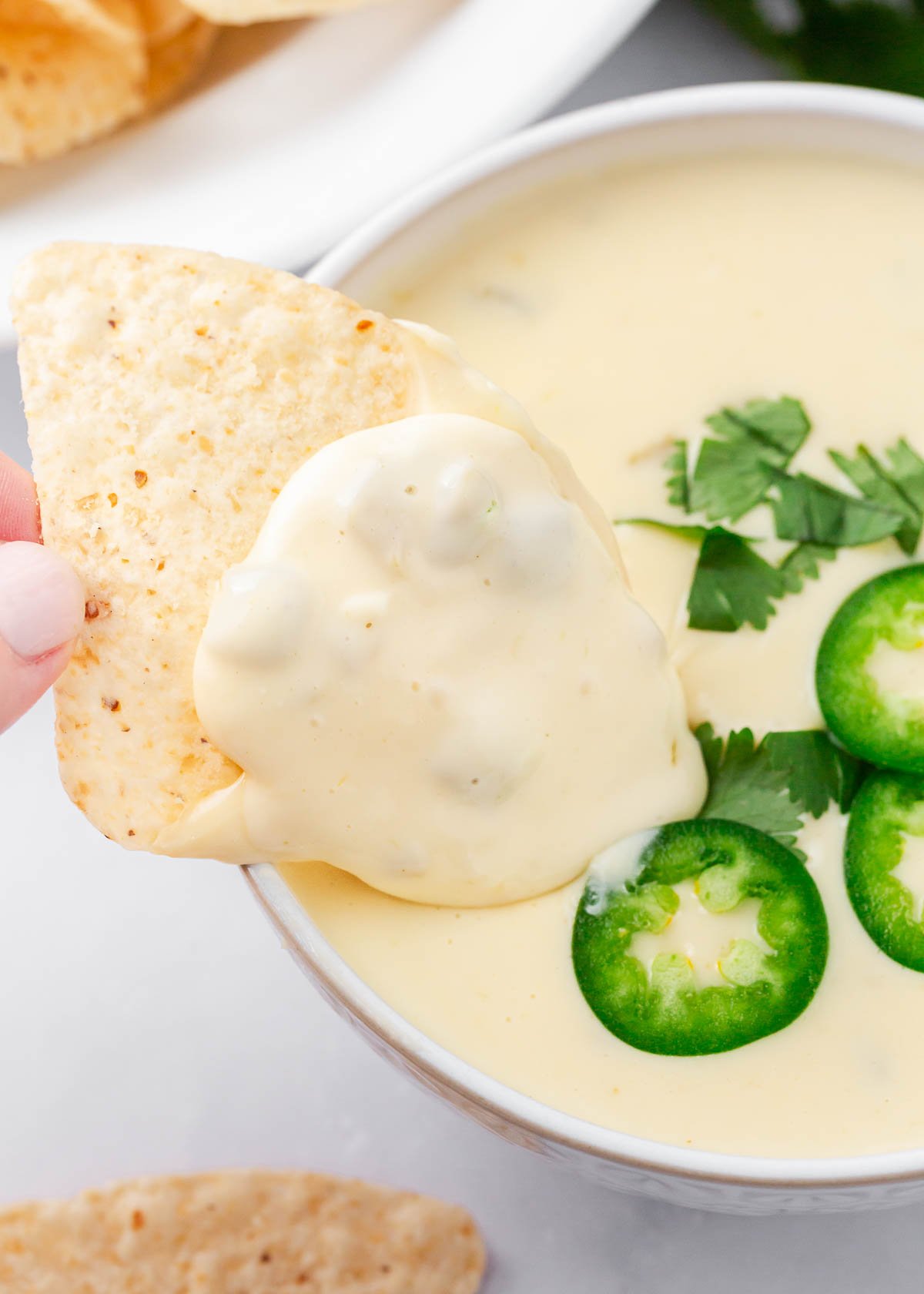 Dipping a tortilla chip in a bowl of queso blanco.