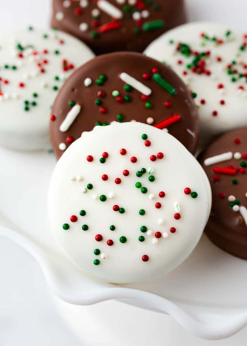 Give regular Oreos a makeover by covering them in white chocolate and decorating them with some festive sprinkles! White Chocolate Covered Oreos are quick to prepare and you only need 2 ingredients! Perfect for holiday tables, lunch box snacks, and even bake sales. White chocolate covered oreos.