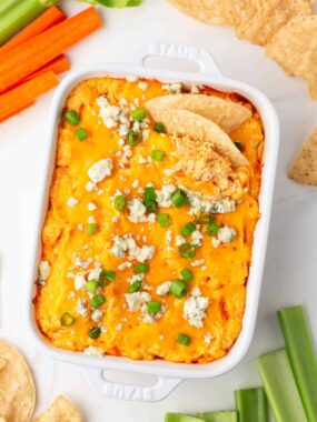 Baked buffalo chicken dip in white baking dish on counter.