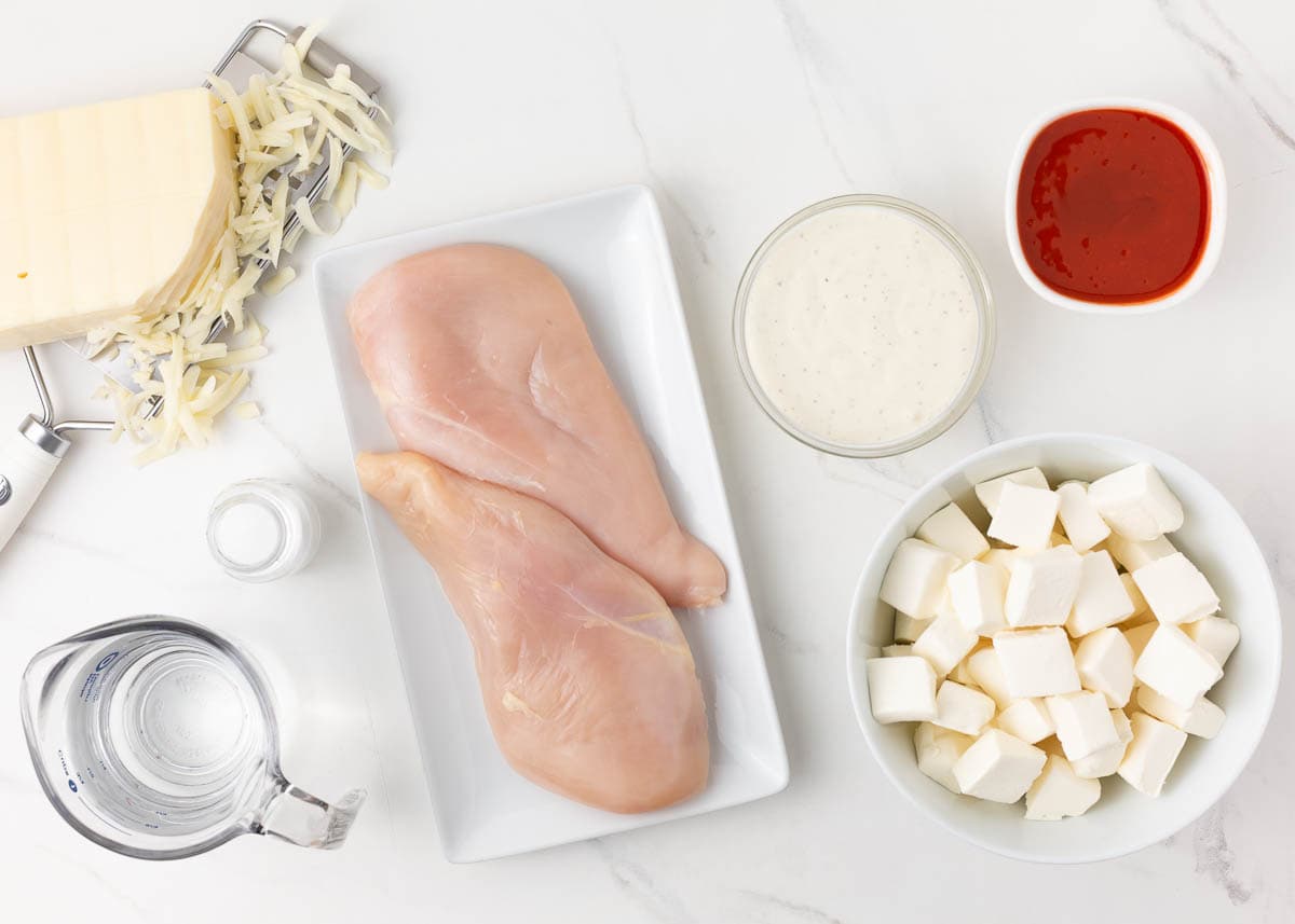 Buffalo chicken dip ingredients on marble counter.