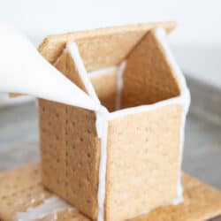 Frosting a gingerbread house with icing.