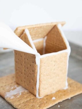 Frosting a gingerbread house with icing.