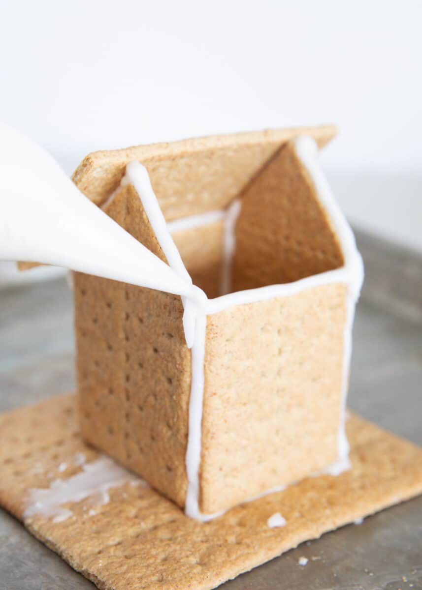 Frosting a gingerbread house with icing.