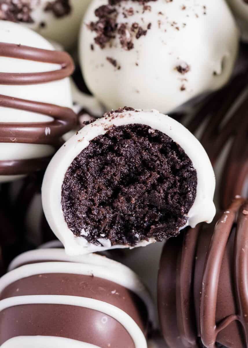 A pile of Oreo balls covered in chocolate with one ball that has a bite taken out of it.