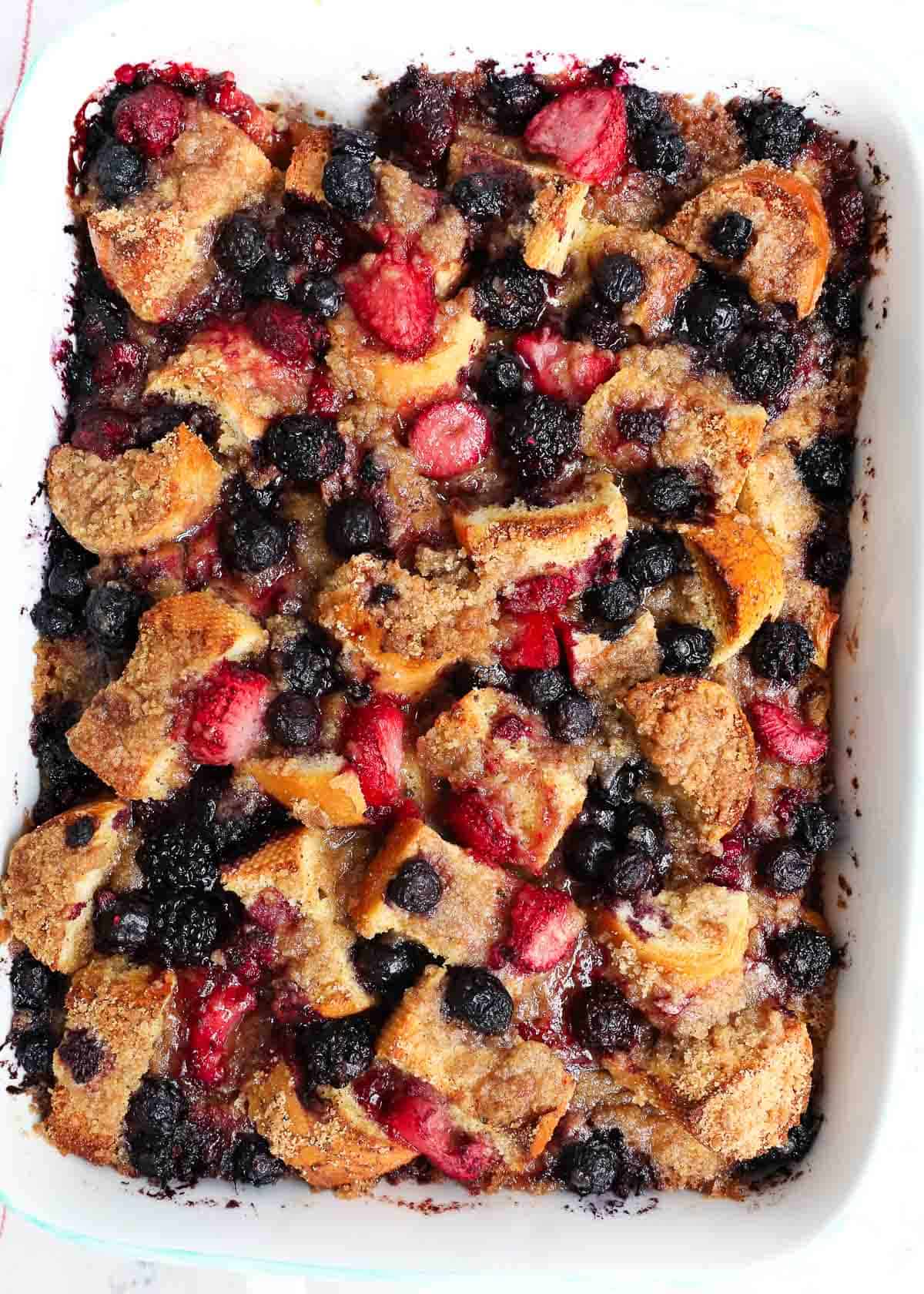 Overnight french toast casserole topped with a brown sugar crumble and berries. A delicious spin on the classic and perfect for holiday gatherings or Sunday brunch! French toast casserole in a white baking dish.