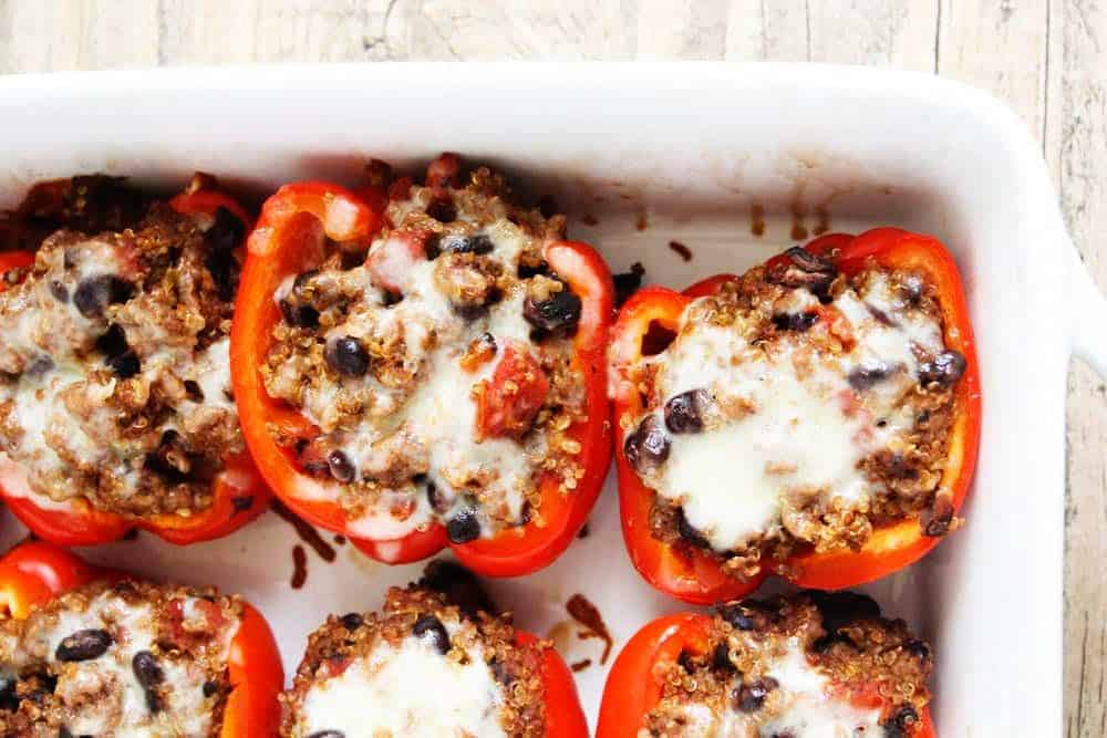 Quinoa stuffed peppers in a white baking dish.