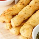 Breadsticks stacked on a wooden board.