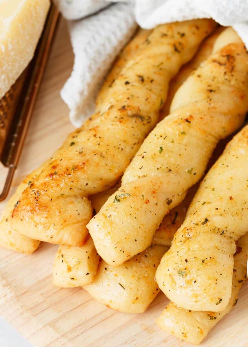 Breadsticks stacked on a wooden board.
