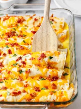 Breakfast enchilada casserole with wooden spoon.