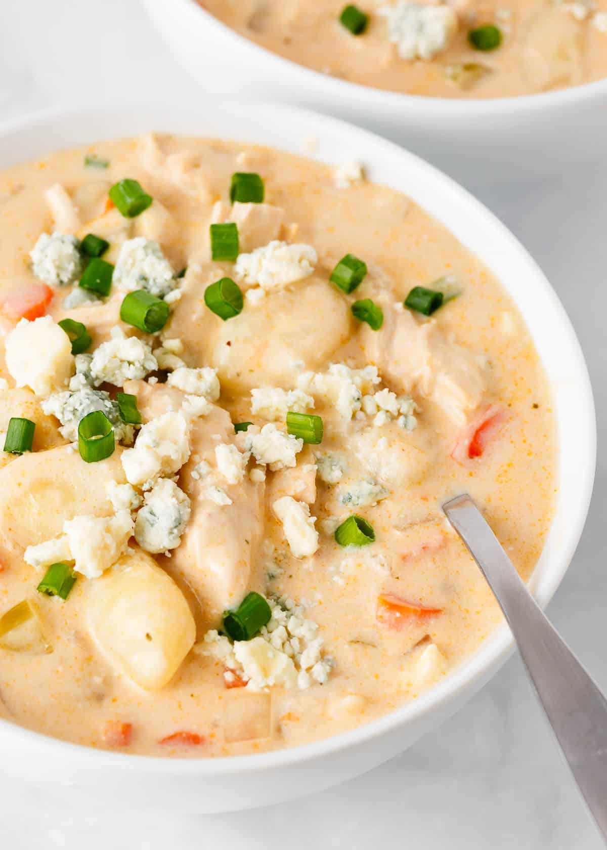 Buffalo chicken soup in a white bowl with spoon.