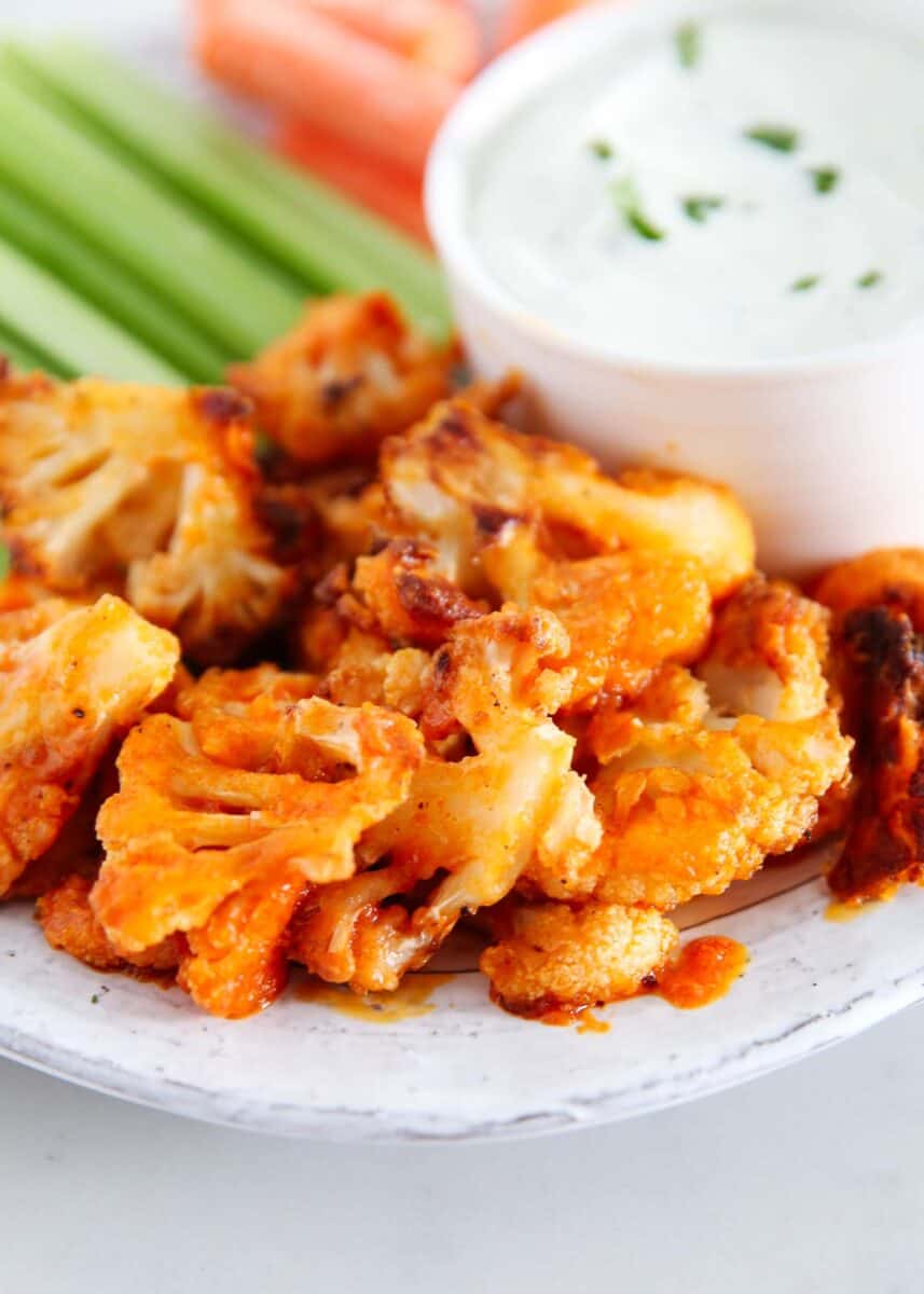 Buffalo cauliflower on a plate with vegetables and a dip.