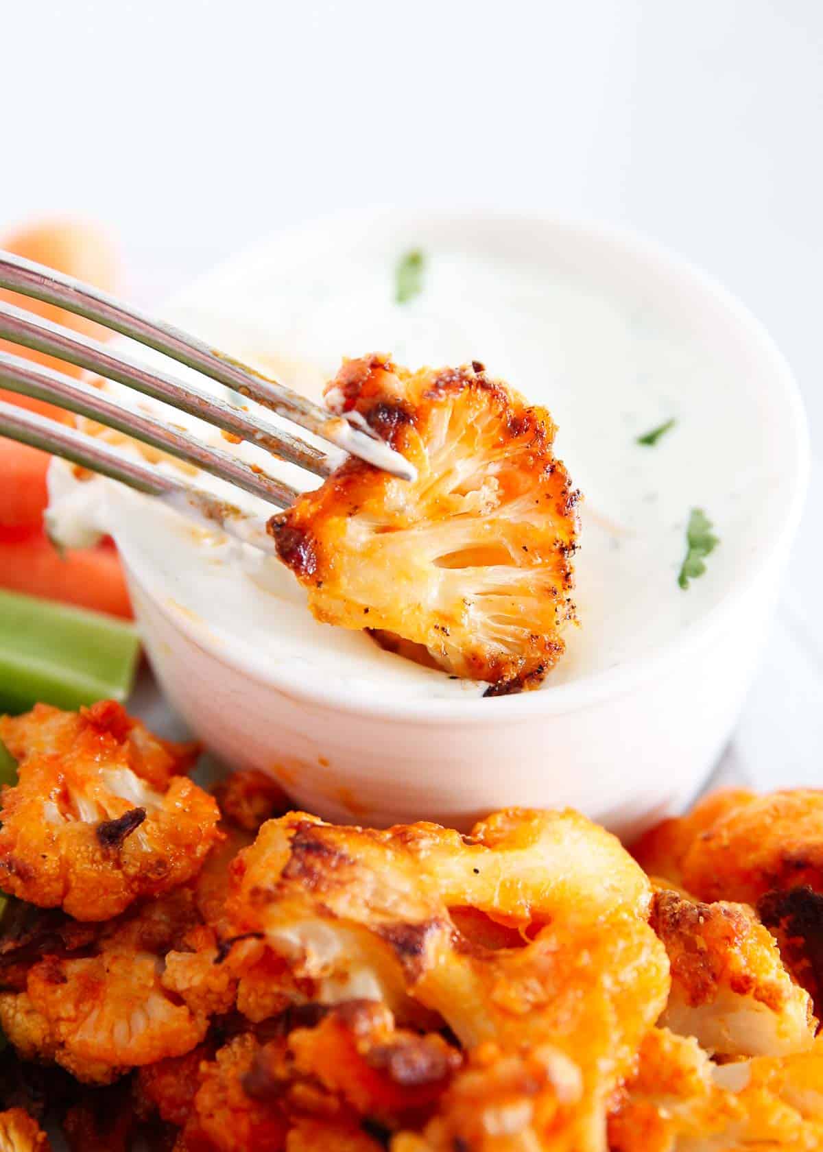 Dipping buffalo cauliflower into dip.