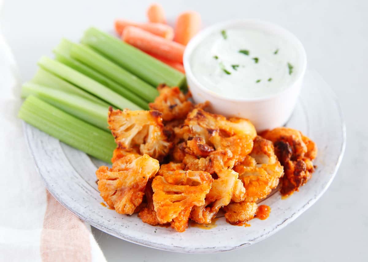 Buffalo cauliflower on a plate with vegetables and dip.
