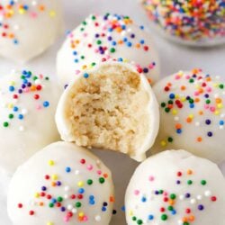 Cake balls with sprinkles and a bite of one taken.