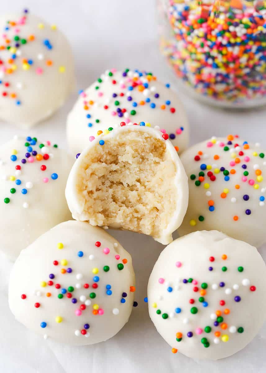 Cake balls with sprinkles and a bite of one taken.