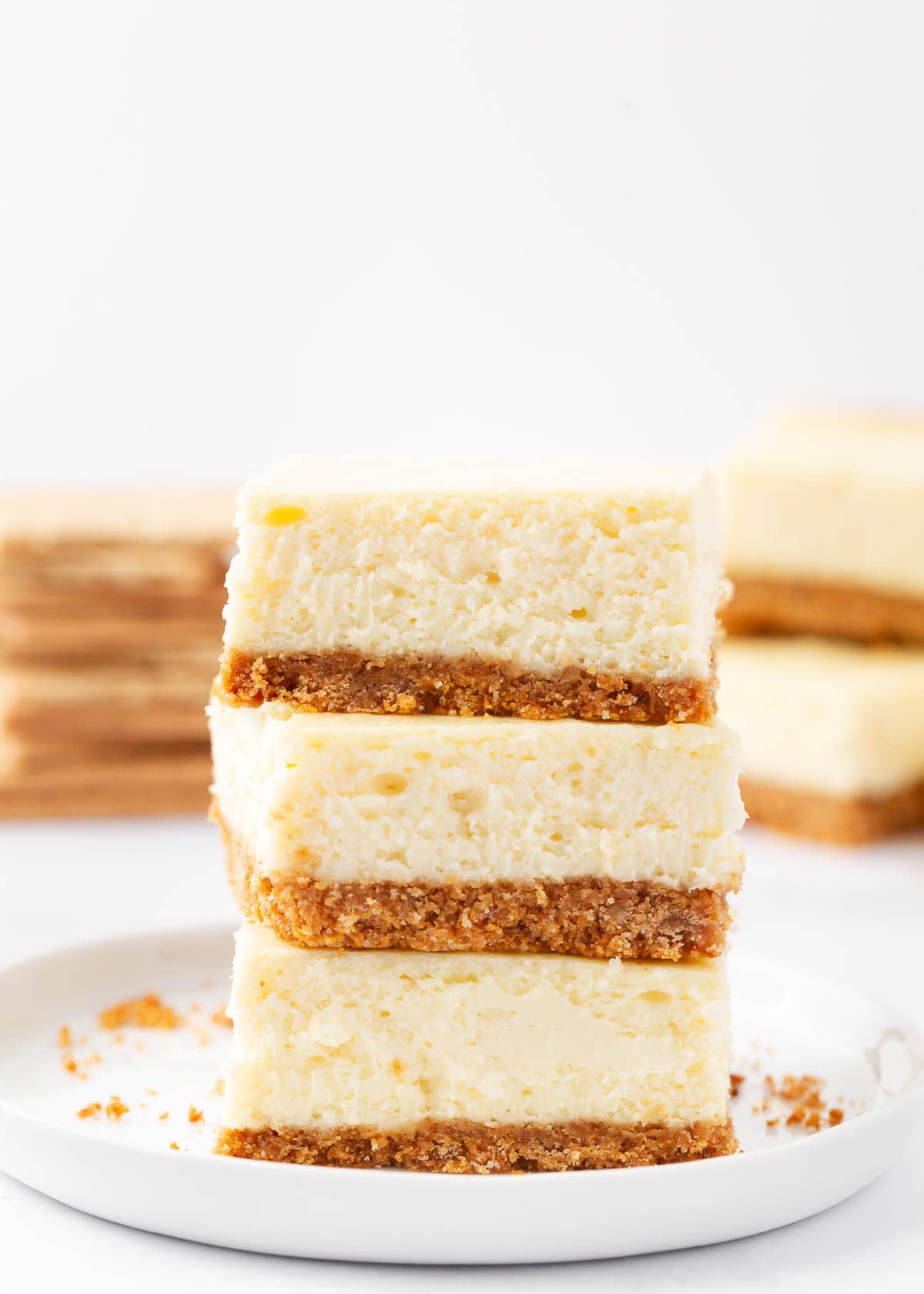 Stack of cheesecake bars on a white plate.