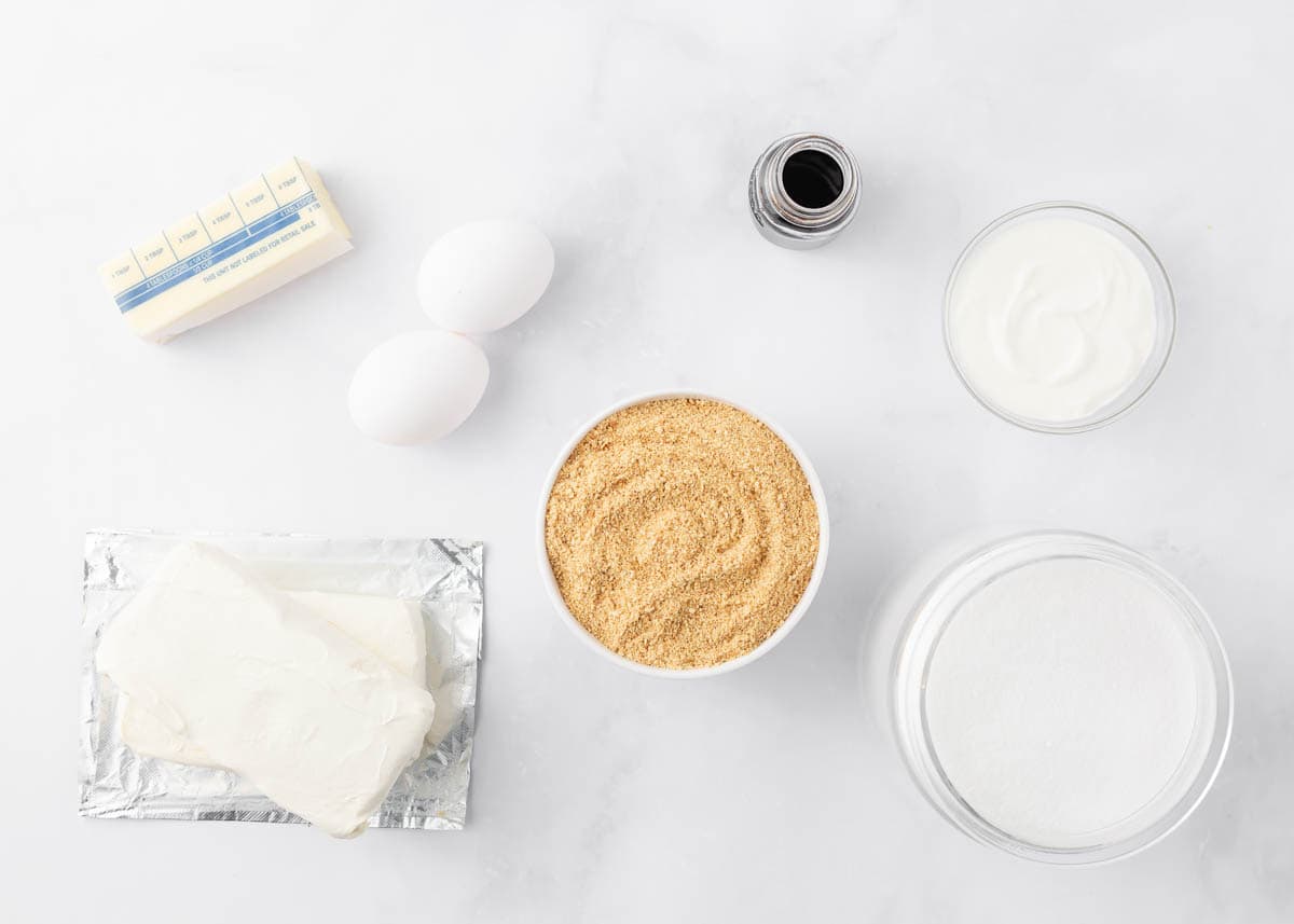 Cheesecake bars ingredients on marble counter.