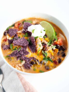 Chicken enchilada soup in white bowl.