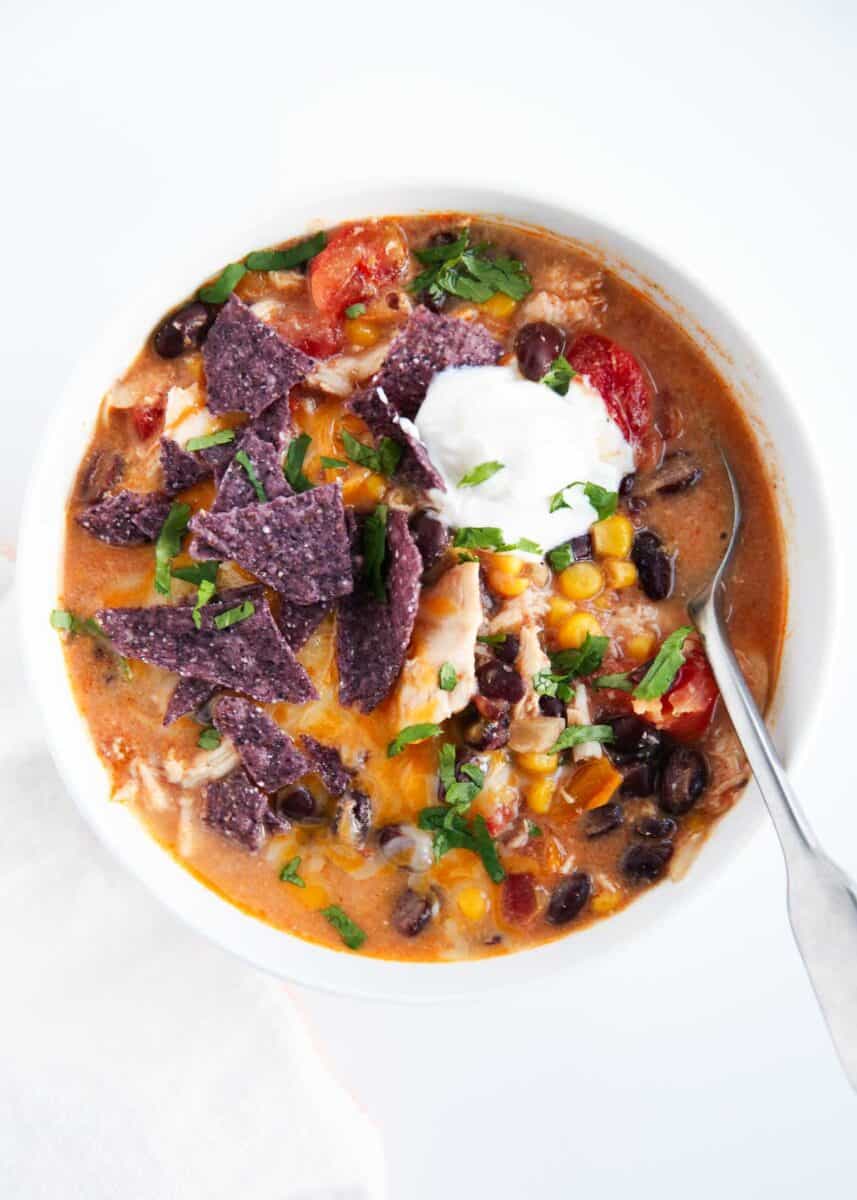 Chicken enchilada soup in white bowl with spoon.