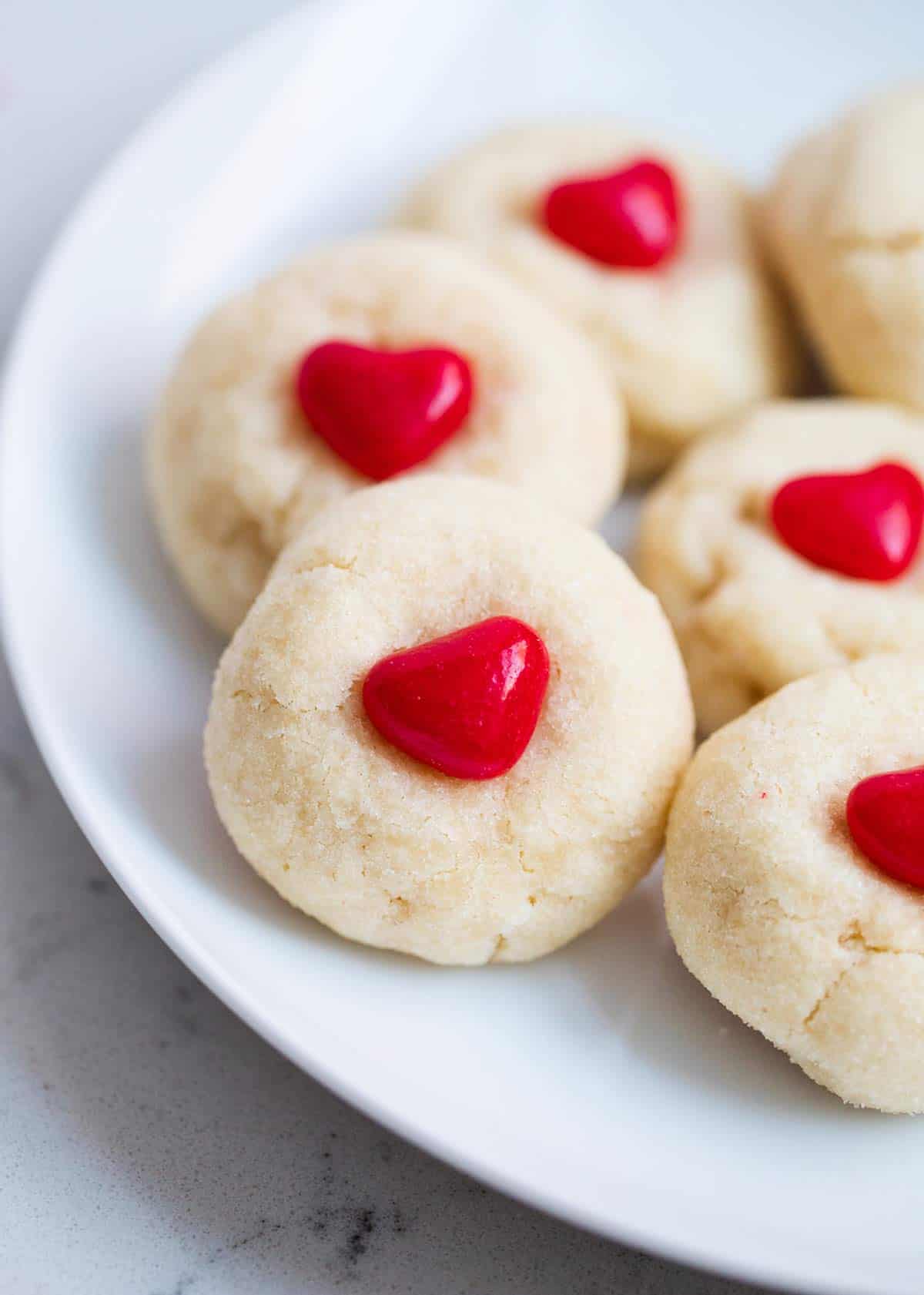 A soft, sweet and easy sugar cookie recipe that's perfect to share with loved ones. These Valentine's Day sugar cookies are rolled in sprinkles or sugar, much easier than classic cut-out cookies! Easy valentine cookies on a plate.