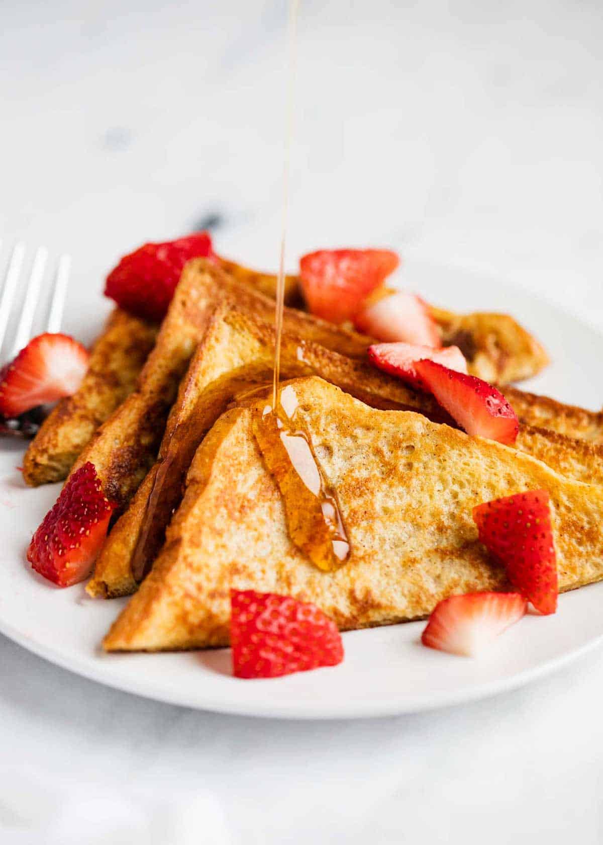 Sliced French toast on a plate with strawberries. 