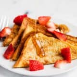 French toast and strawberries on a plate with syrup.