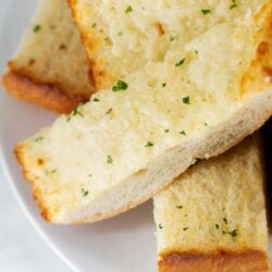 Sliced garlic bread on a white plate.