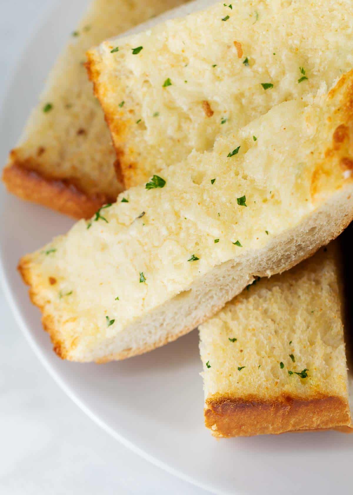 Sliced garlic bread on a white plate.