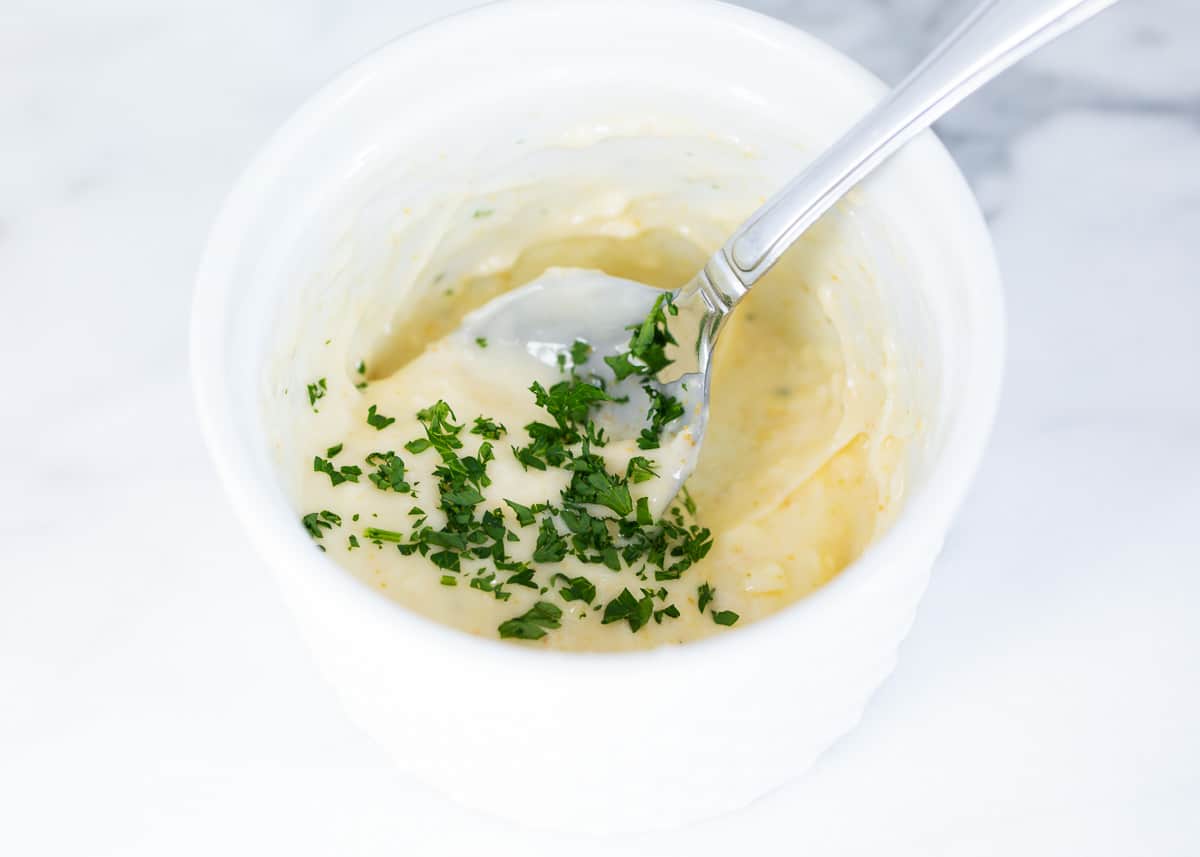 Mixing butter and parsley in a bowl.