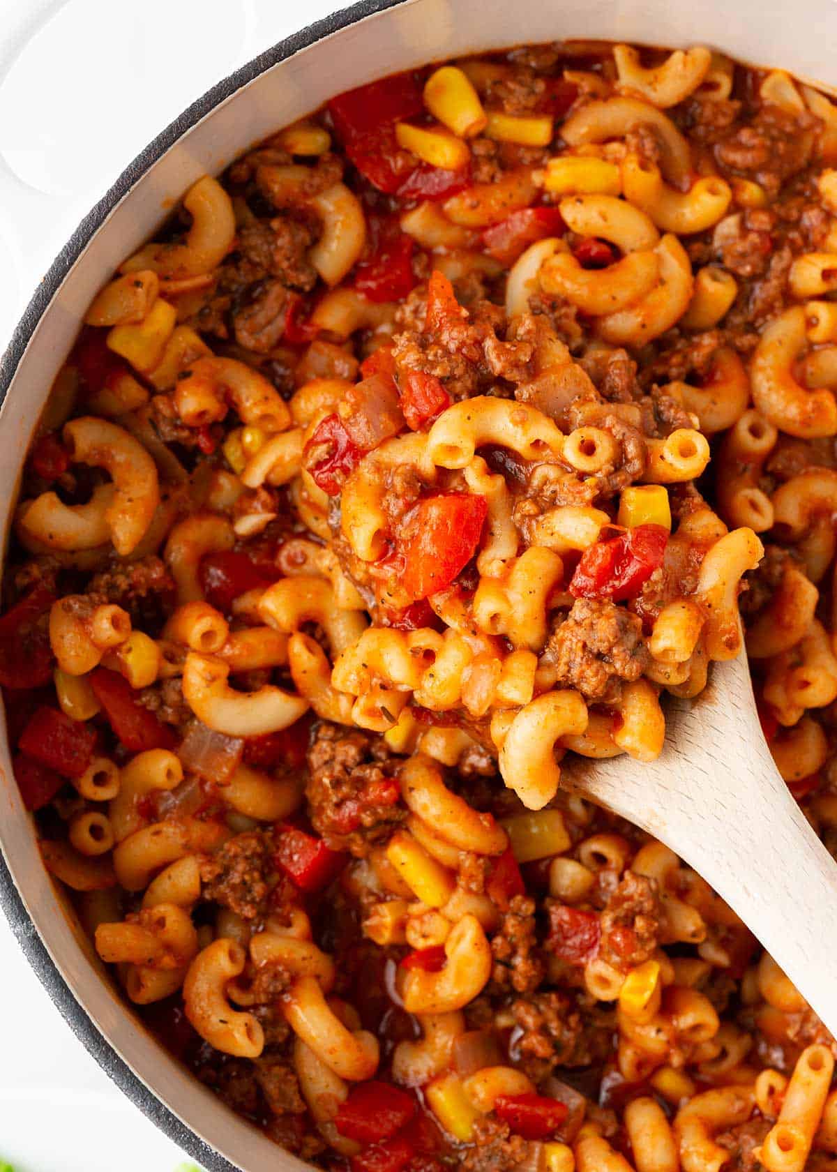 Goulash in a white pot with wooden spoon.