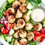 Greek meatballs on top of a salad in a bowl.