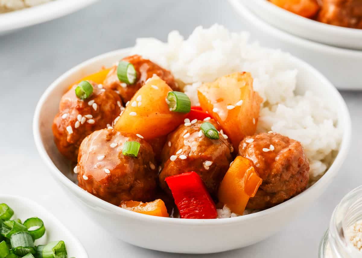 Hawaiian meatballs in a bowl with pineapple and rice.