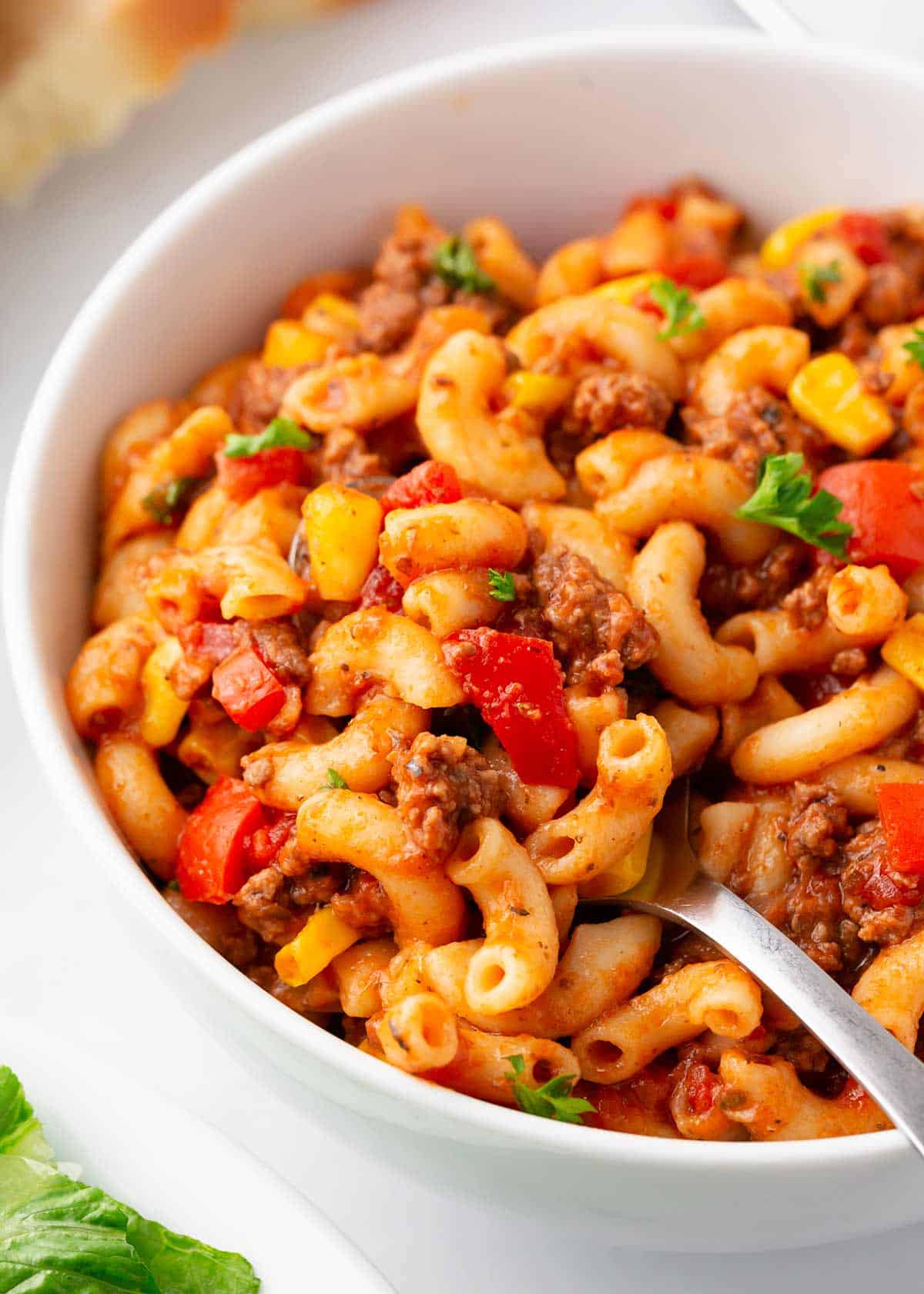 Goulash in a white bowl with a spoon. 