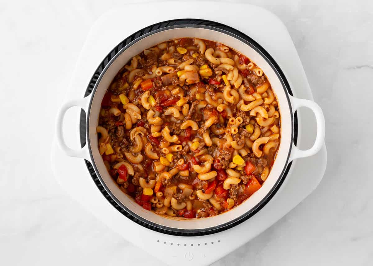 Finished American goulash in a white pot before adding cheese on top.