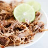 Instant pot carnitas on a white plate with lime.