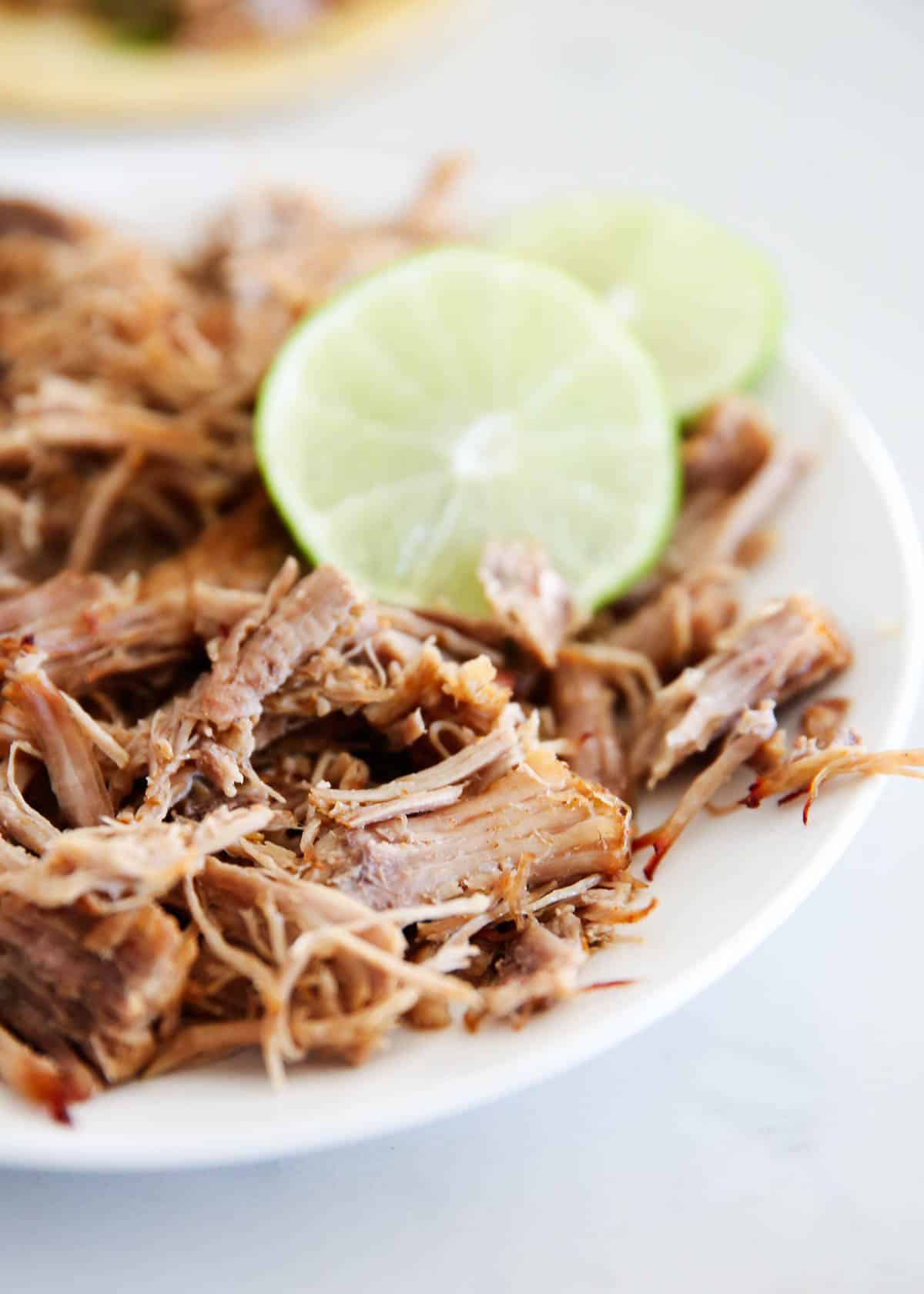 Instant pot carnitas on a white plate with lime.