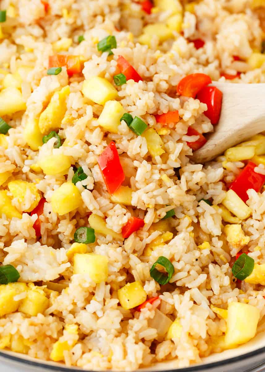 Pineapple fried rice in a pot with wooden spoon.