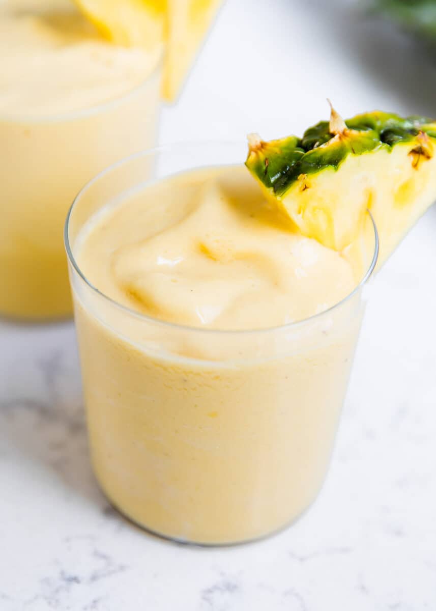This healthy pineapple smoothie is creamy, refreshing and tastes downright tropical. It's easy to make in only 5 minutes with 5 ingredients and is perfect for breakfast, snack, or anytime you crave something sweet and fruity! Pineapple smoothie in glass cup.