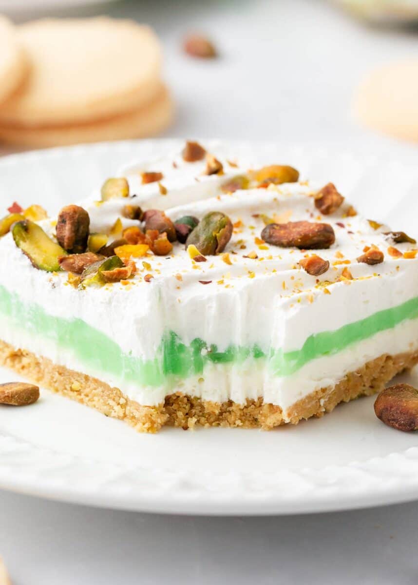 For a cool and creamy dessert that is as easy as it is impressive try this delicious Pistachio Dessert! Layers of shortbread, cream cheese, pistachio pudding, and whipped topping come together to create this perfectly light treat. Layered pistachio dessert on plate.