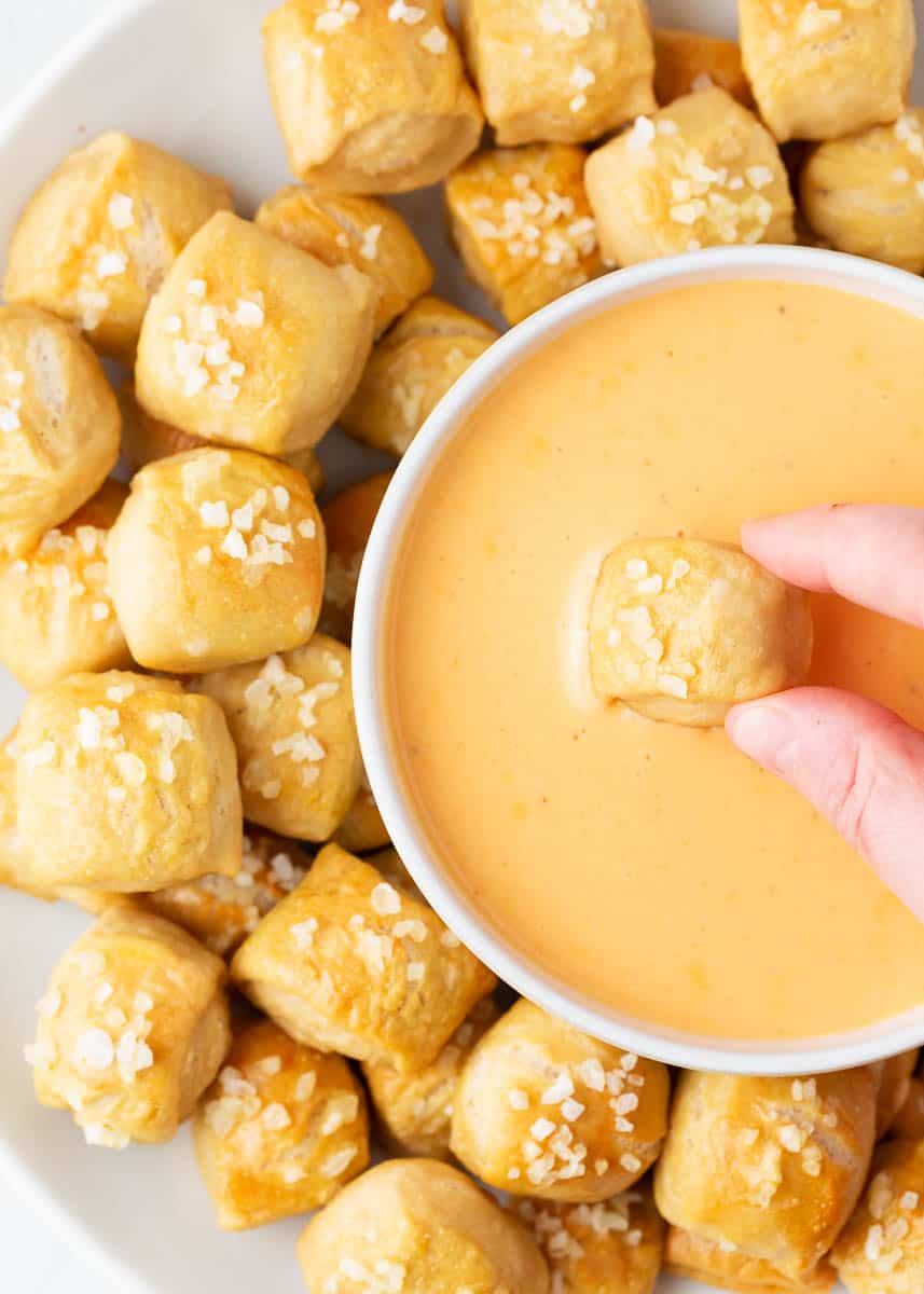 Dipping pretzel bites into cheese sauce.