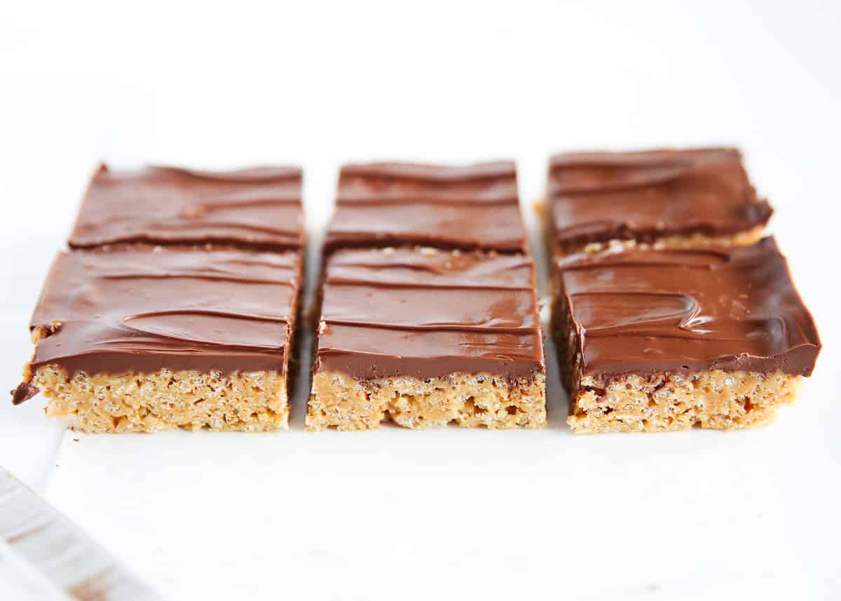 Chewy, crispy peanut butter scotcheroos that are topped with a chocolate and butterscotch ganache. This easy recipe is the perfect no-bake treat! Scotcheroos on counter.