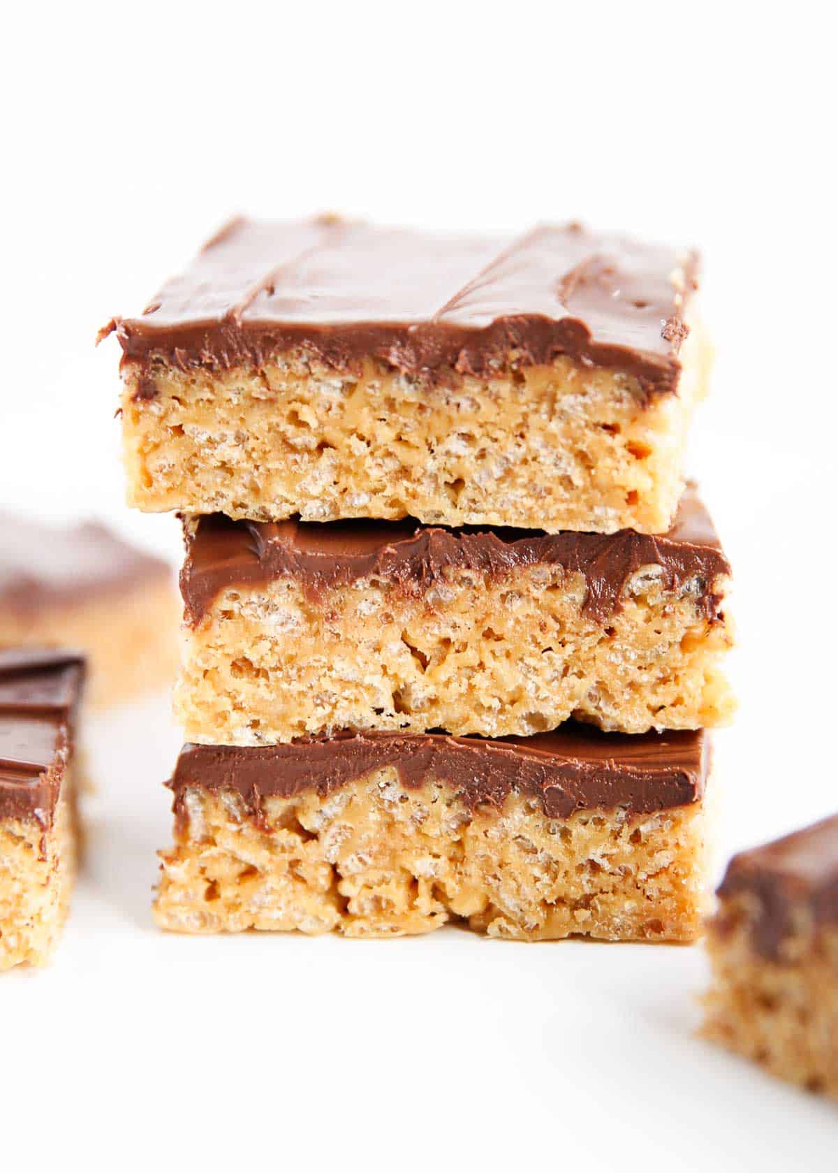 Chewy, crispy peanut butter scotcheroos that are topped with a chocolate and butterscotch ganache. This easy recipe is the perfect no-bake treat! Soft and chewy scotcheroos on white counter.
