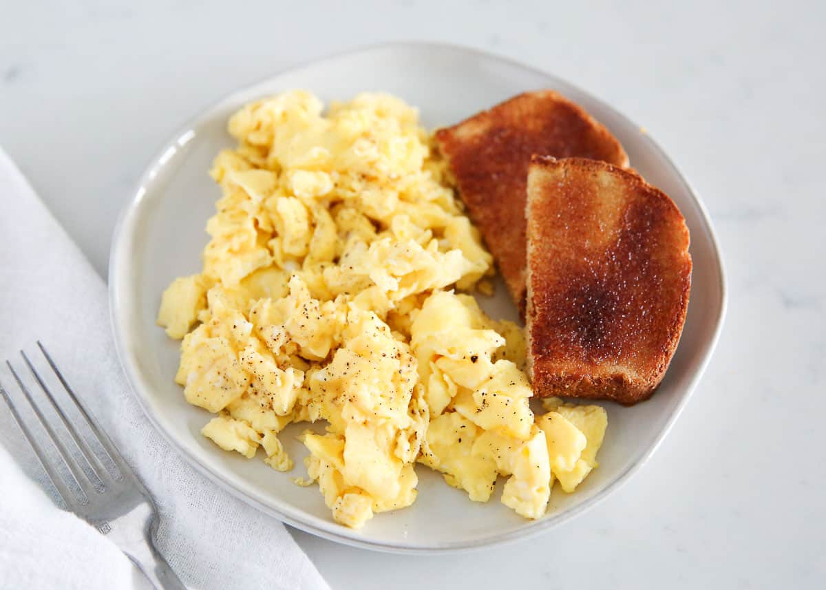 Scrambled eggs on a plate with toast.