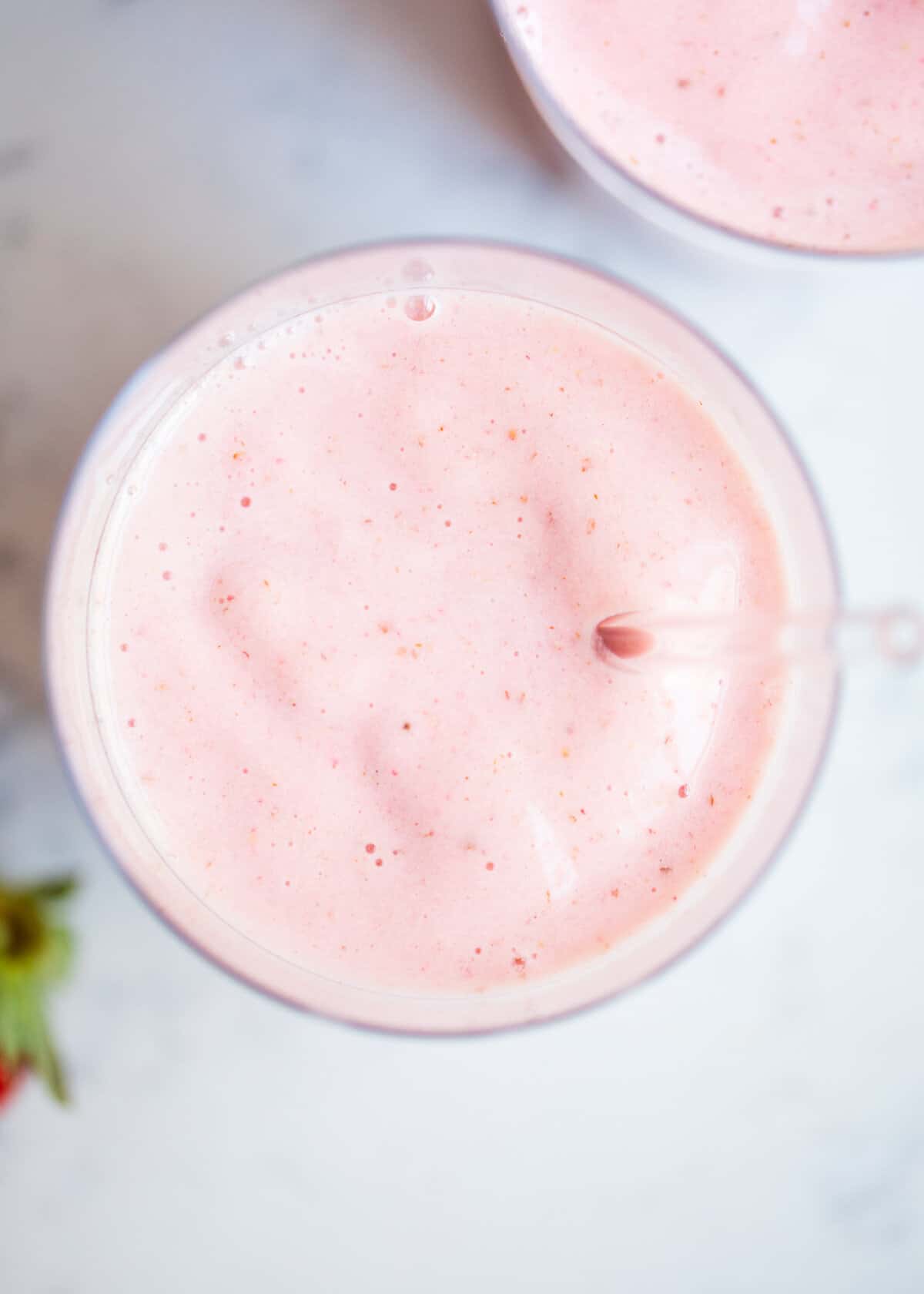 Strawberry banana smoothie in a glass cup with a straw.