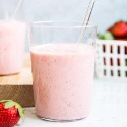 Strawberry banana smoothie in a glass cup on counter.