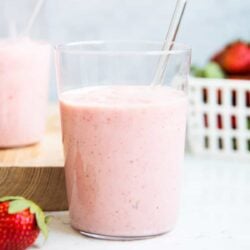 Strawberry banana smoothie in a glass cup on counter.