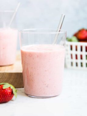 Strawberry banana smoothie in a glass cup on counter.