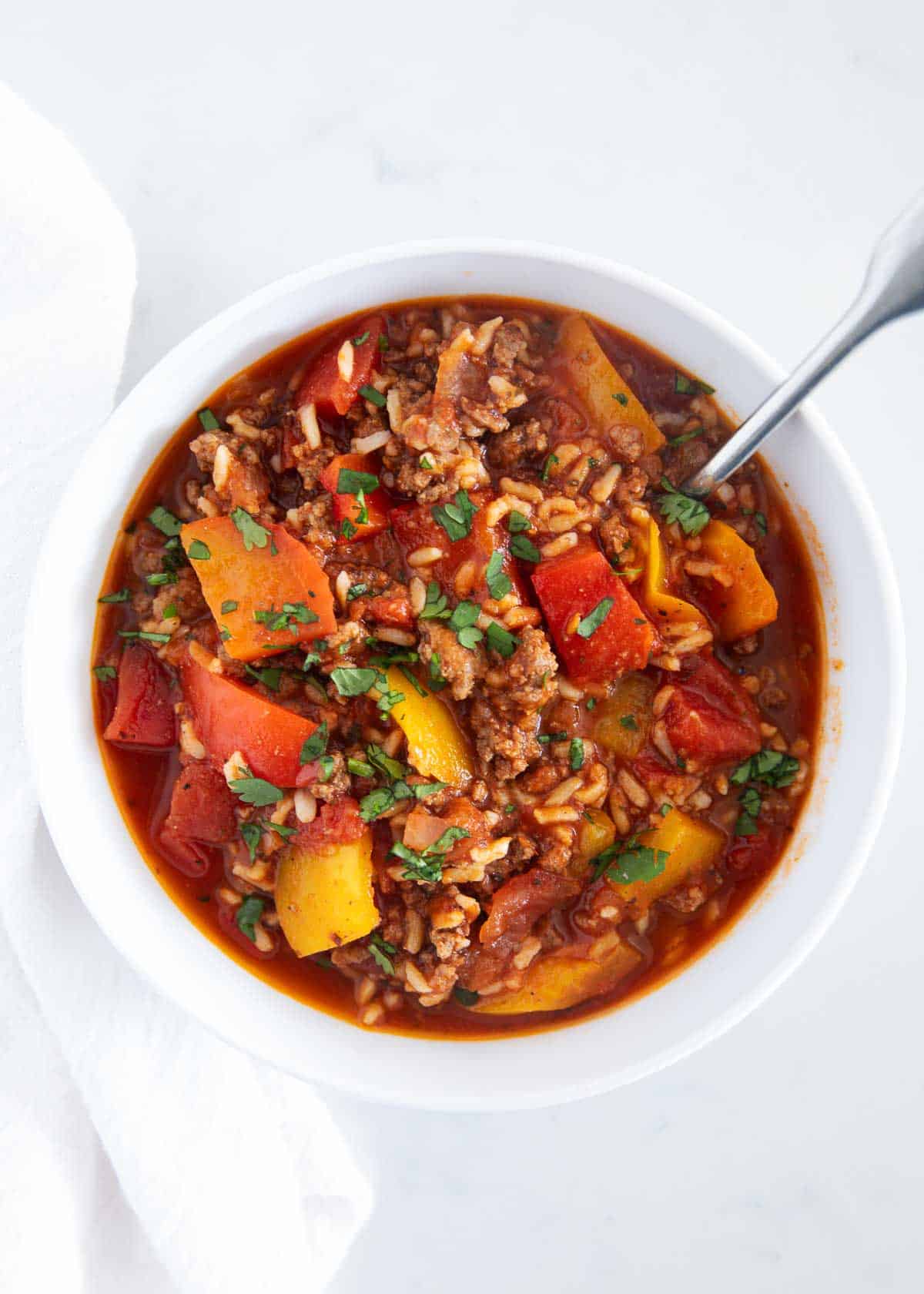 An overhead photo shot of red pepper soup in a white bowl. 