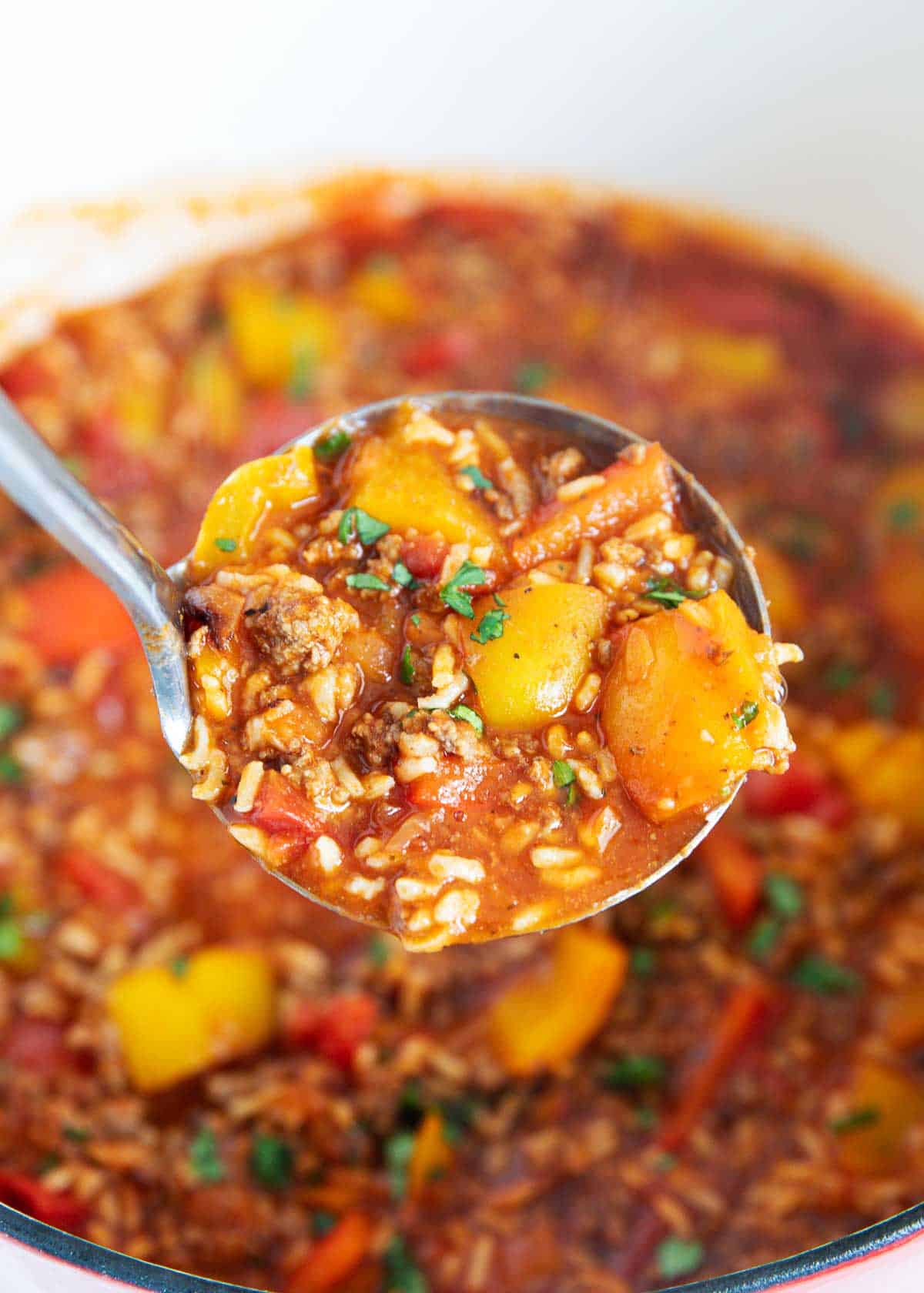 A ladle lifting the stuffed pepper soup up to the camera. 